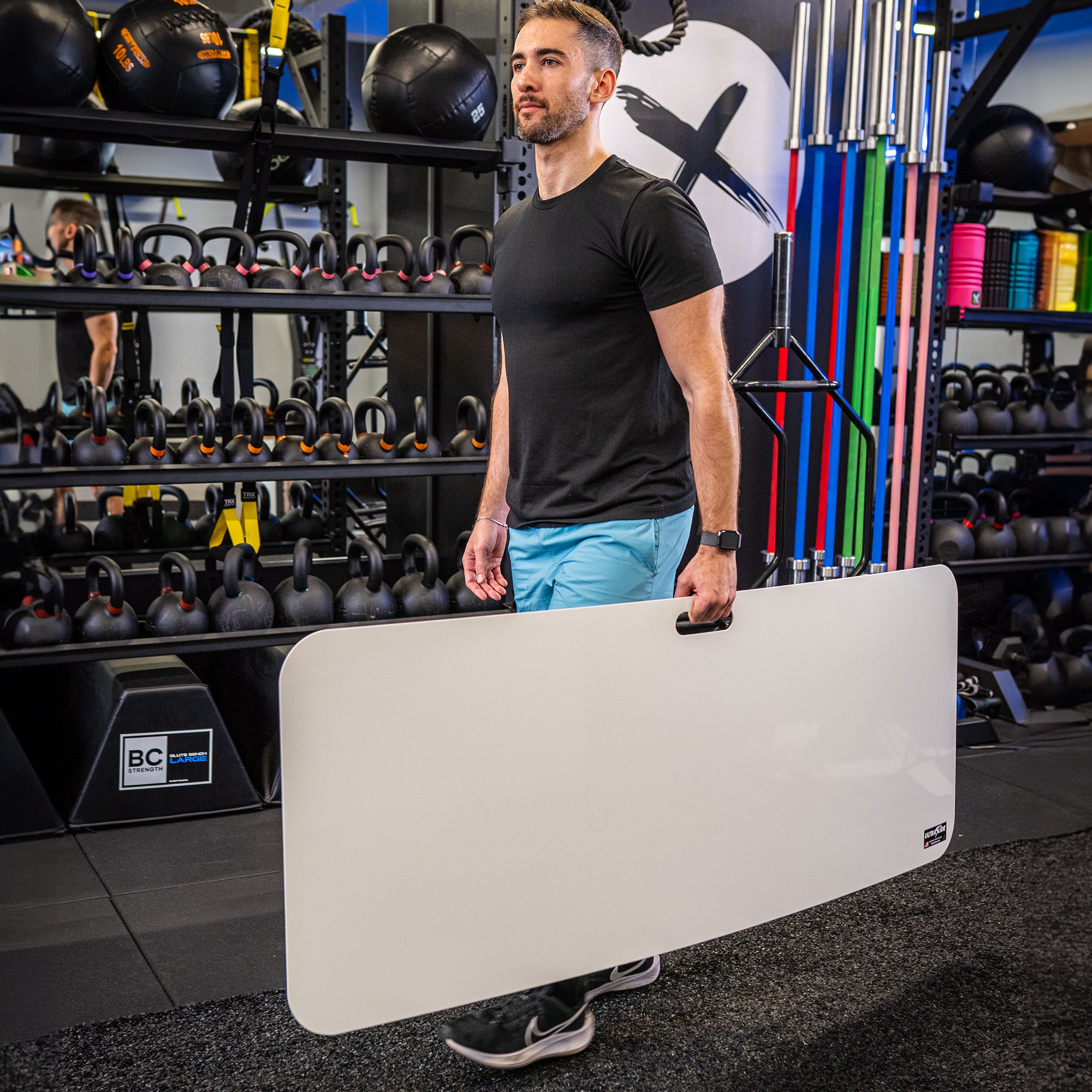 Man carrying an ULTRASLIDE slide board with its built-in handle