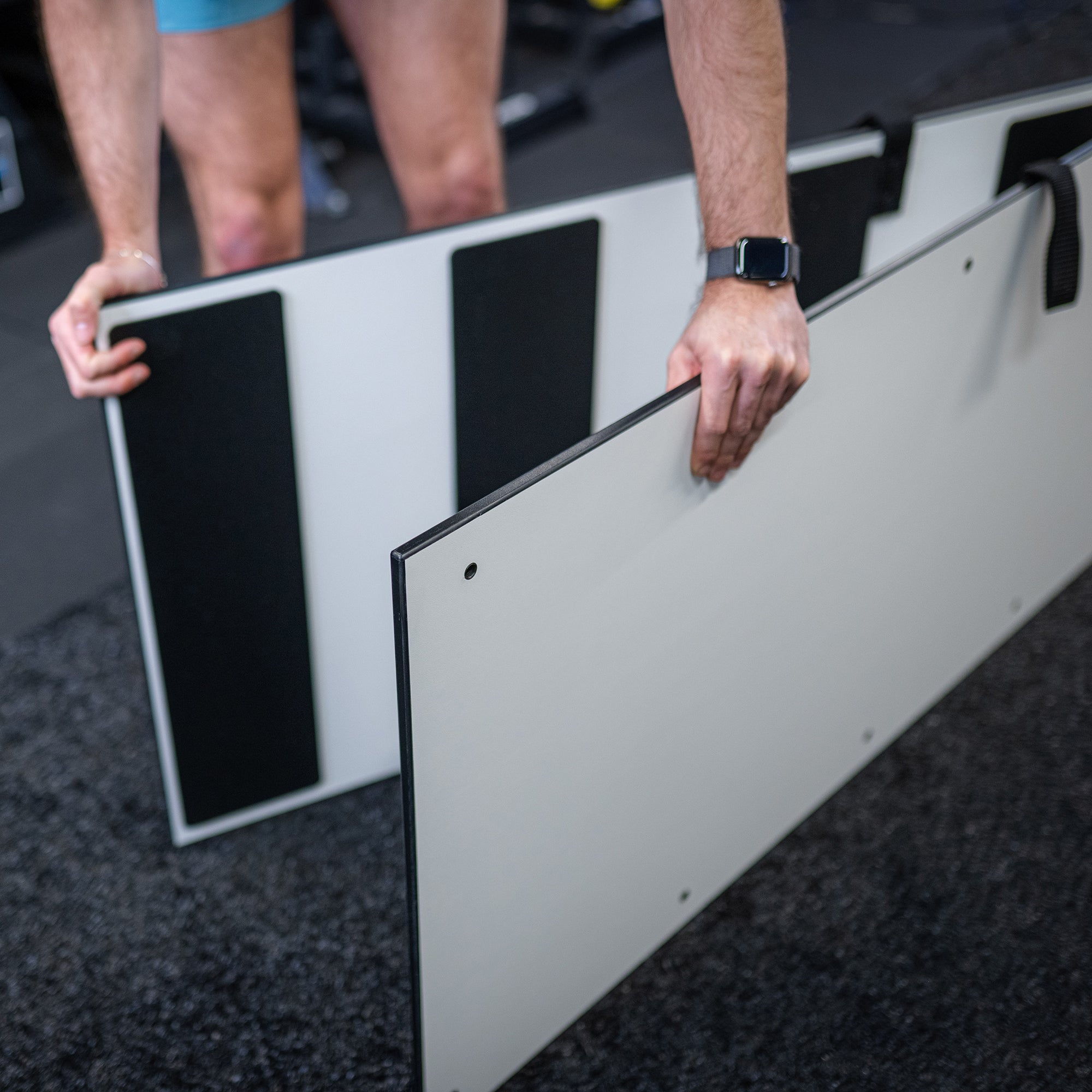 Person holding an Ultraslide slide board on a dark floor