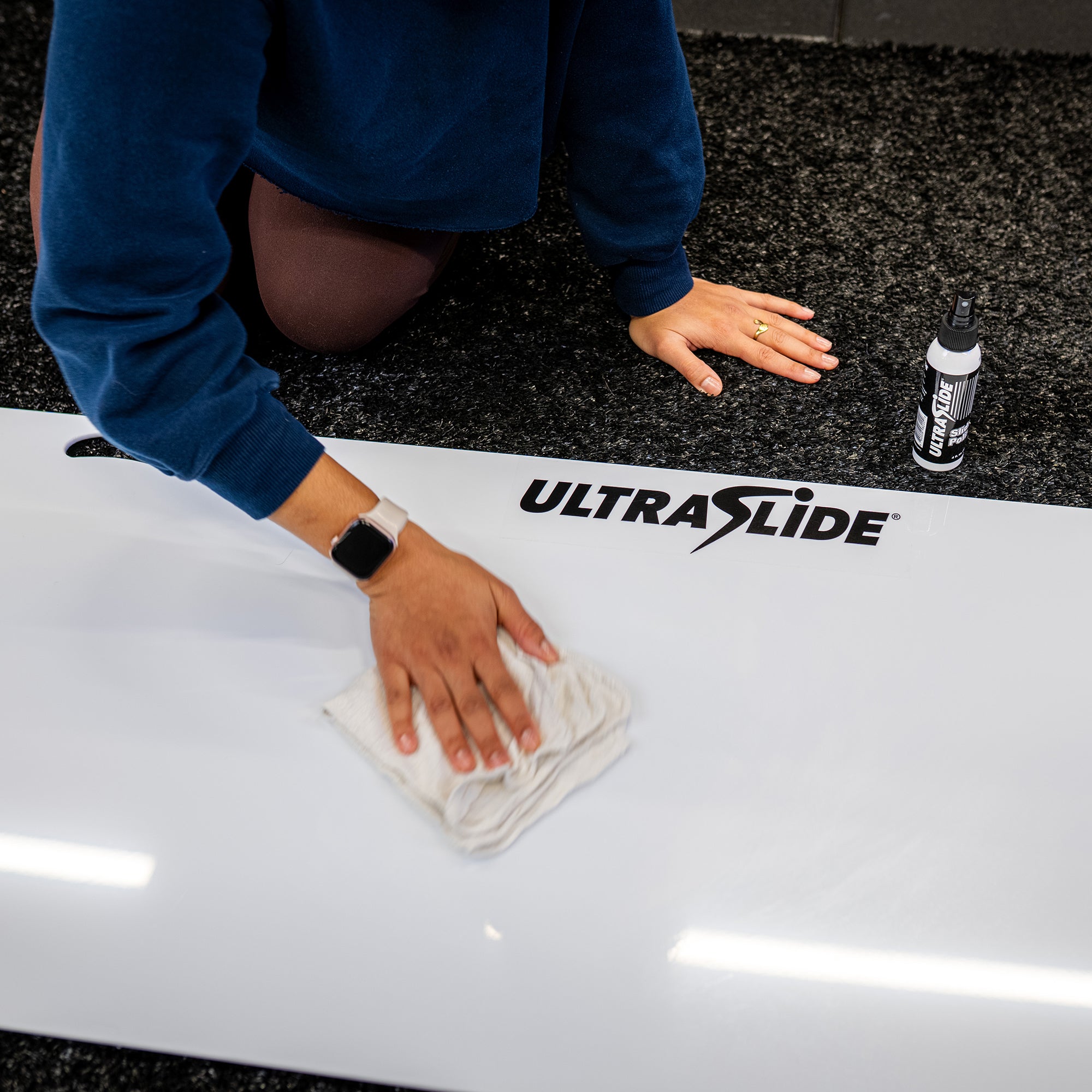 ULTRASLIDE Slide Polish being applied to a slide board with a rag