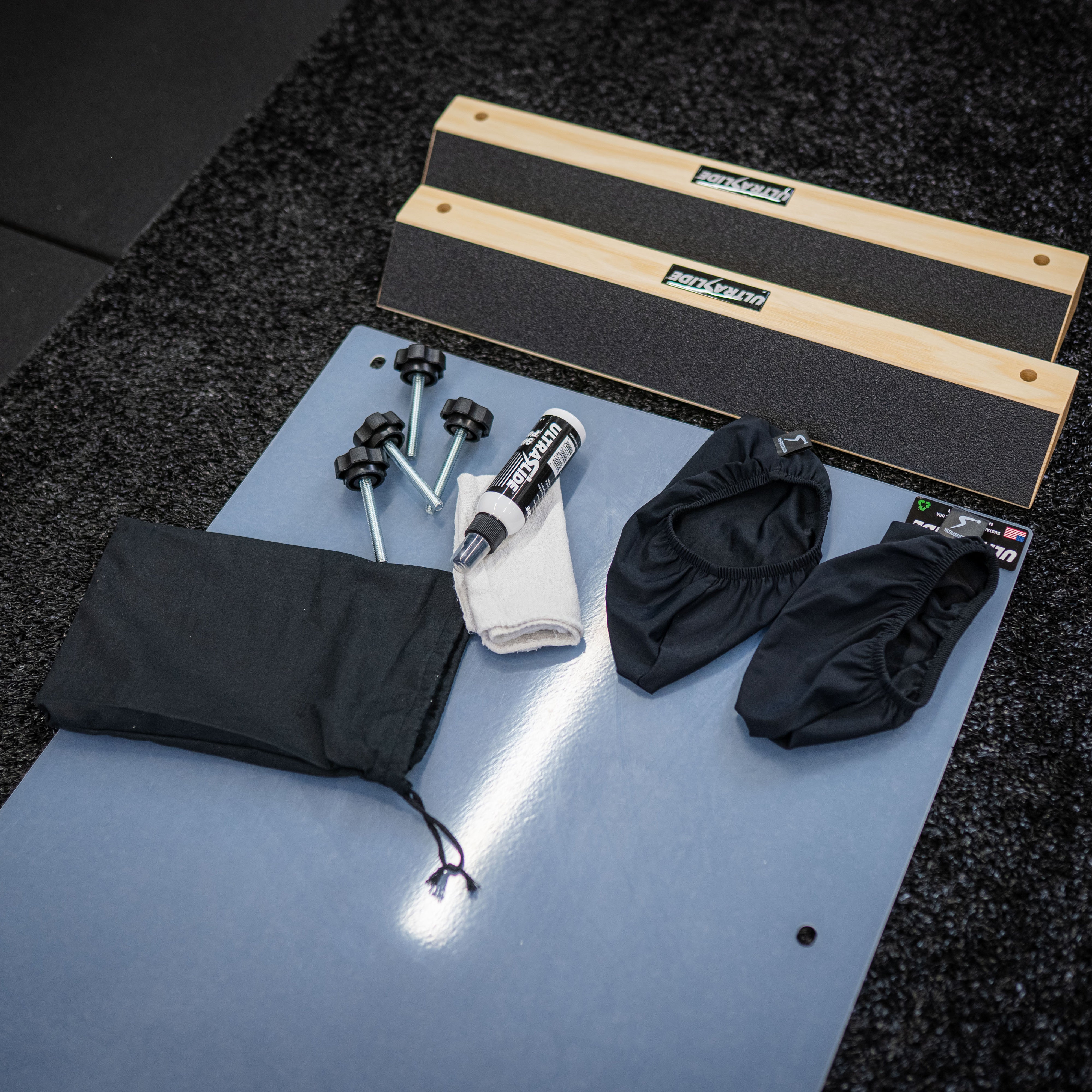 ULTRASLIDE slide board and accessories on a dark floor.