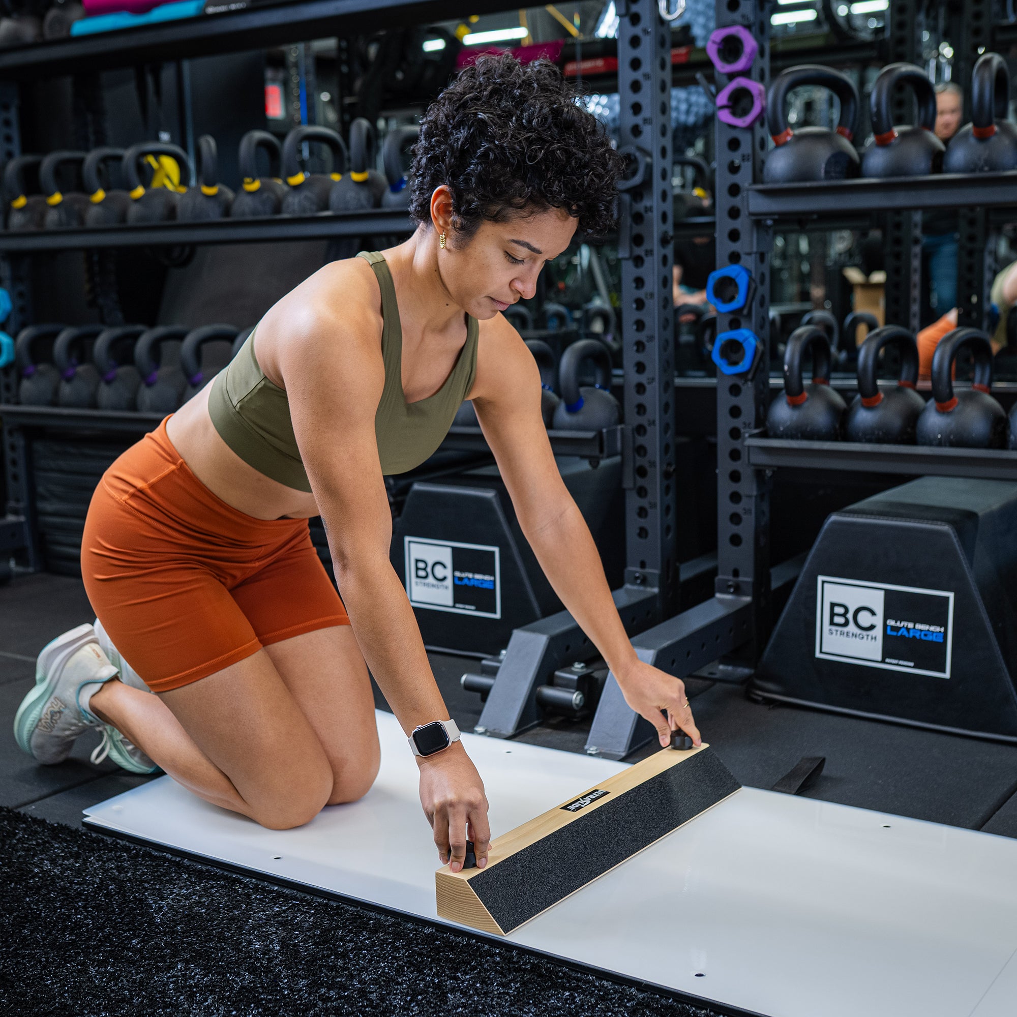 Woman in a gym adjusting length of an ULTRASLIDE slide board on a mat.