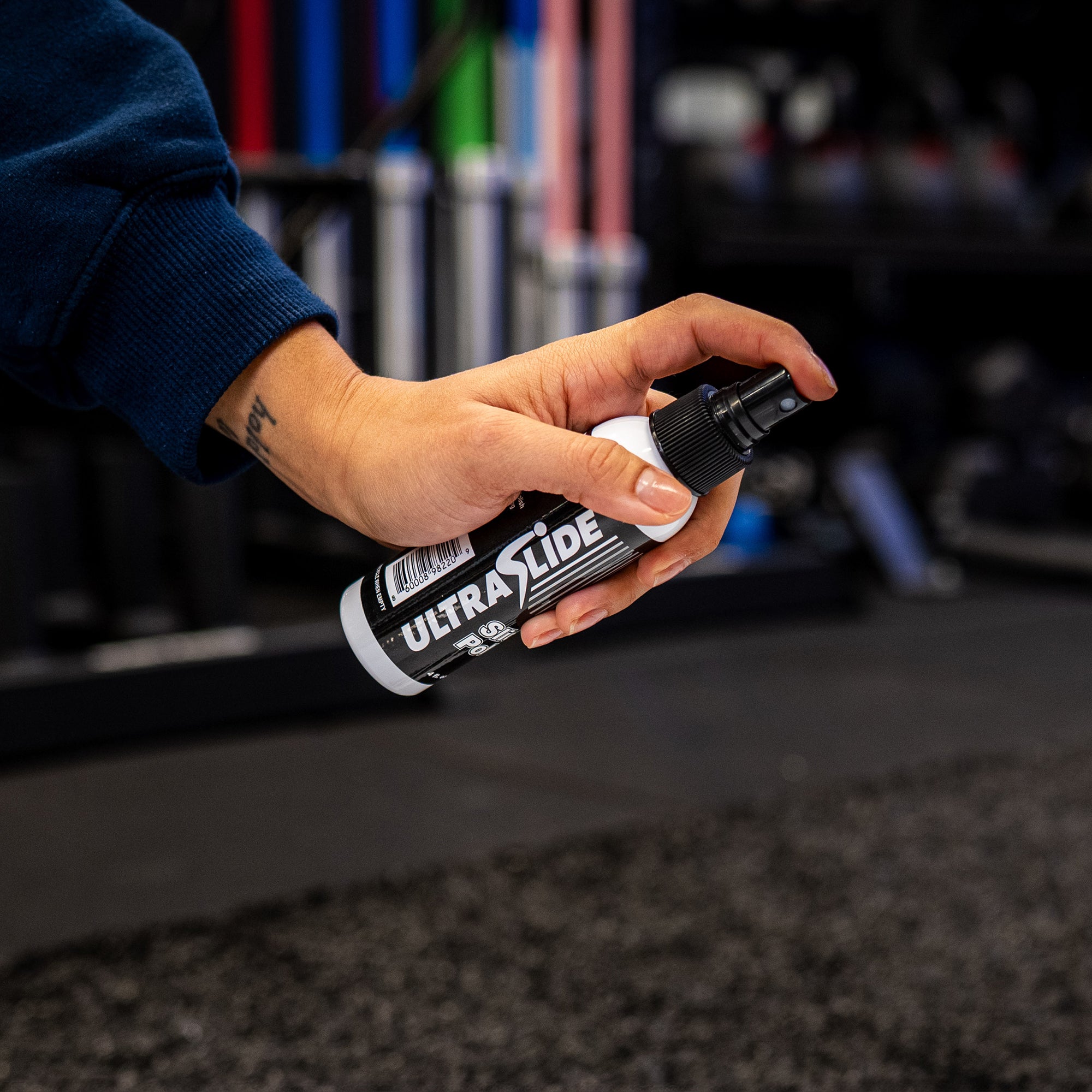 Hand holding a bottle of UltraSlide Slide Polish with a blurred background